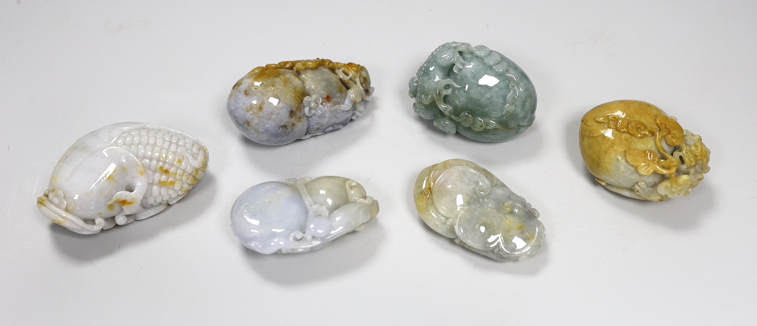 Six Chinese jadeite 'pebble' carvings including one of bars and fruit, 8cm wide
